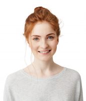 Portrait of happy tender ginger girl with blue eyes and freckles looking at camera smiling over white background. Copy space.